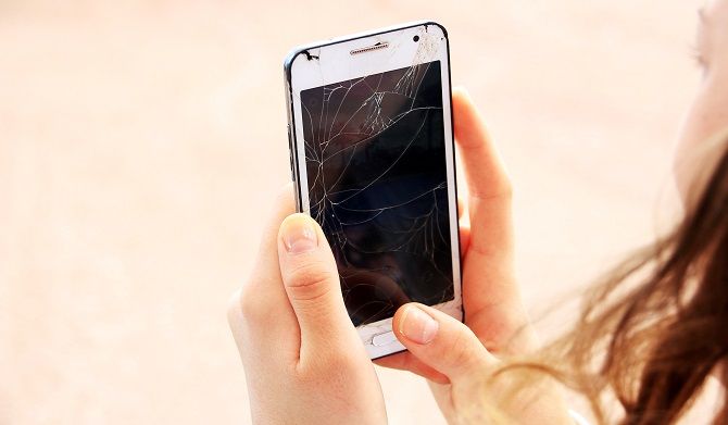 A woman holding a broken smartphone
