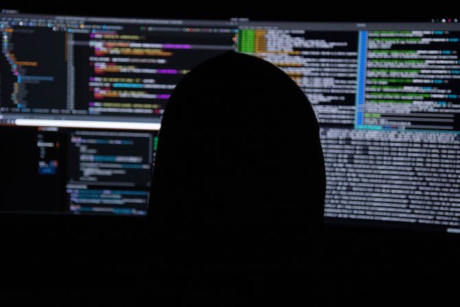 Person in shadow looking at computer monitors